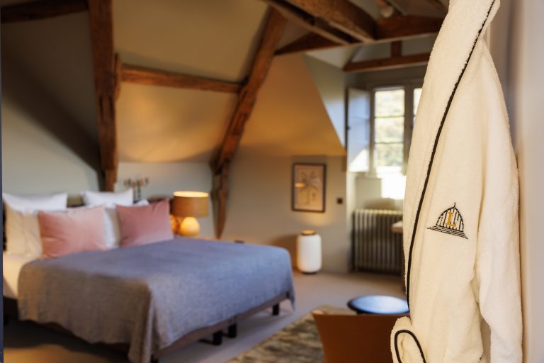 Chambre Deluxe parc au château locguénolé poutres et meubles en bois, fauteuil et table basse, fenêtre et peignoir