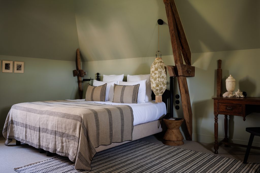 Lit dressé et lampe en papier à coté d'un bureau en bois ancien avec coquillages et autres décorations de mer de la chambre deluxe mer de notre hotel de luxe en bretagne