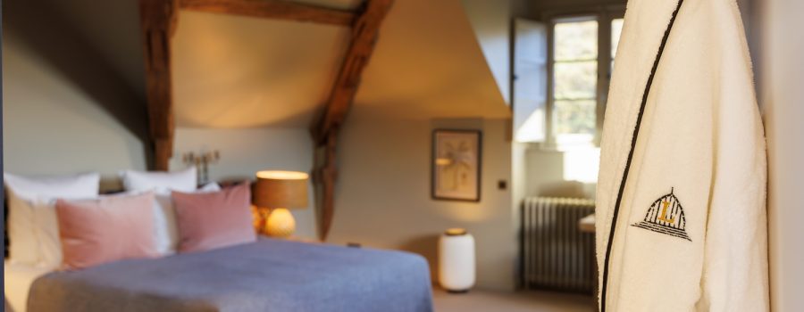 Chambre Deluxe parc au château locguénolé poutres et meubles en bois, fauteuil et table basse, fenêtre et peignoir
